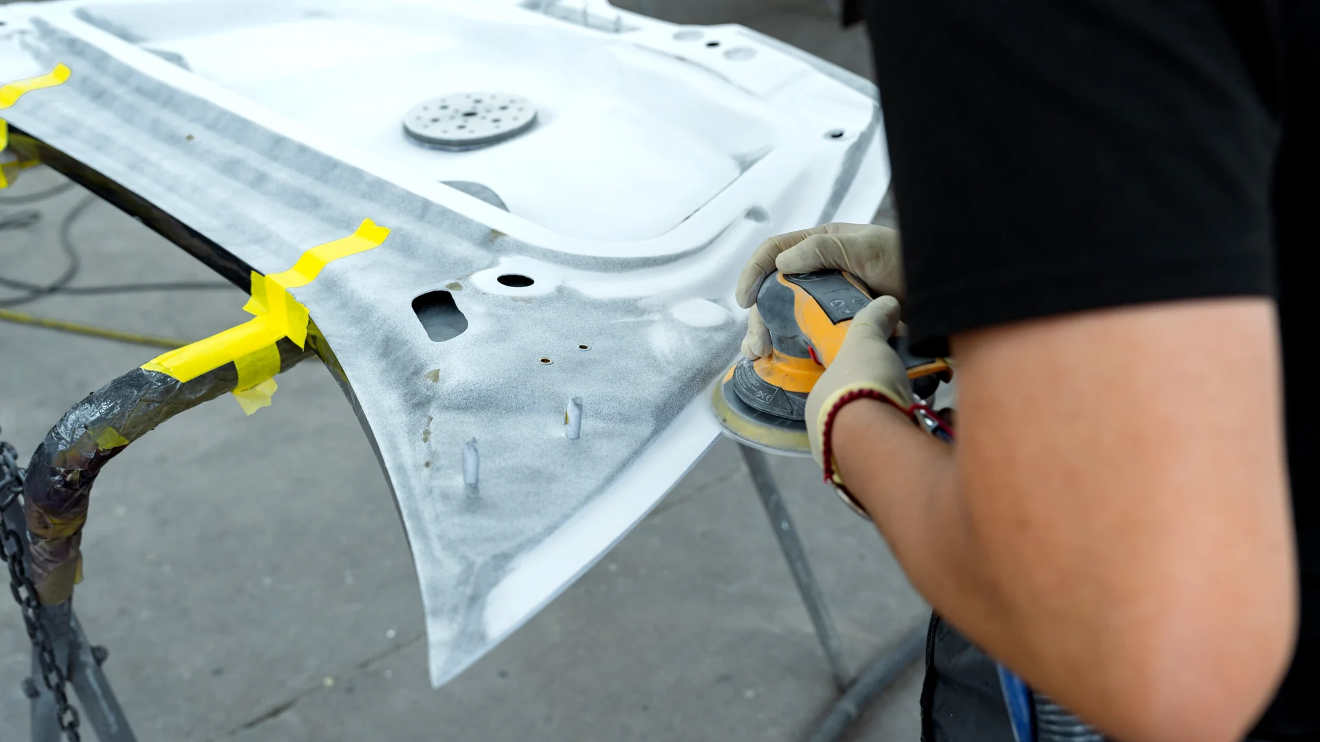 Gloved hands sanding a panel at Palladium Auto Body in Hayward.